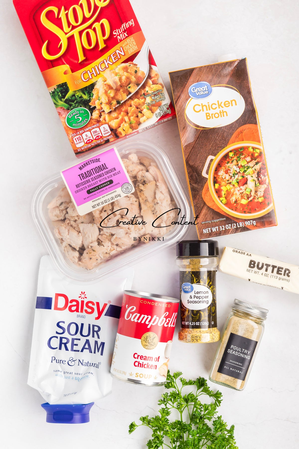 Ingredients for a Church Cookbook Chicken Casserole - Exclusive, including a box of stuffing mix, chicken broth, cooked chicken breast, sour cream, cream of chicken soup, butter, and seasonings.