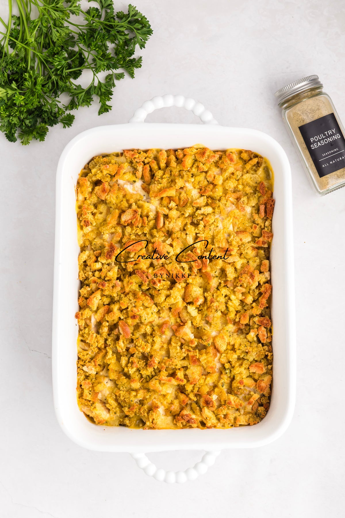Church cookbook chicken casserole in a white baking dish with parsley and poultry seasoning