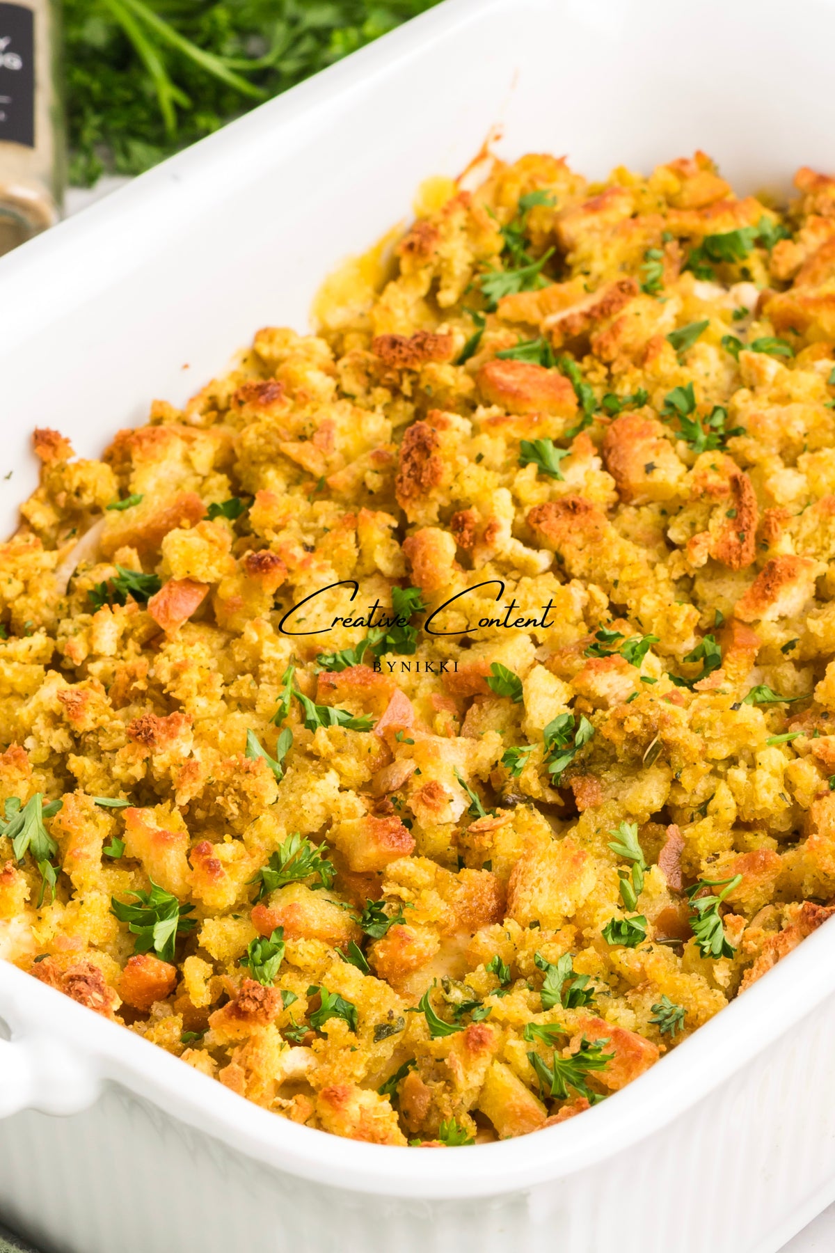 Church cookbook chicken casserole with a golden brown breadcrumb topping and fresh parsley in a white baking dish