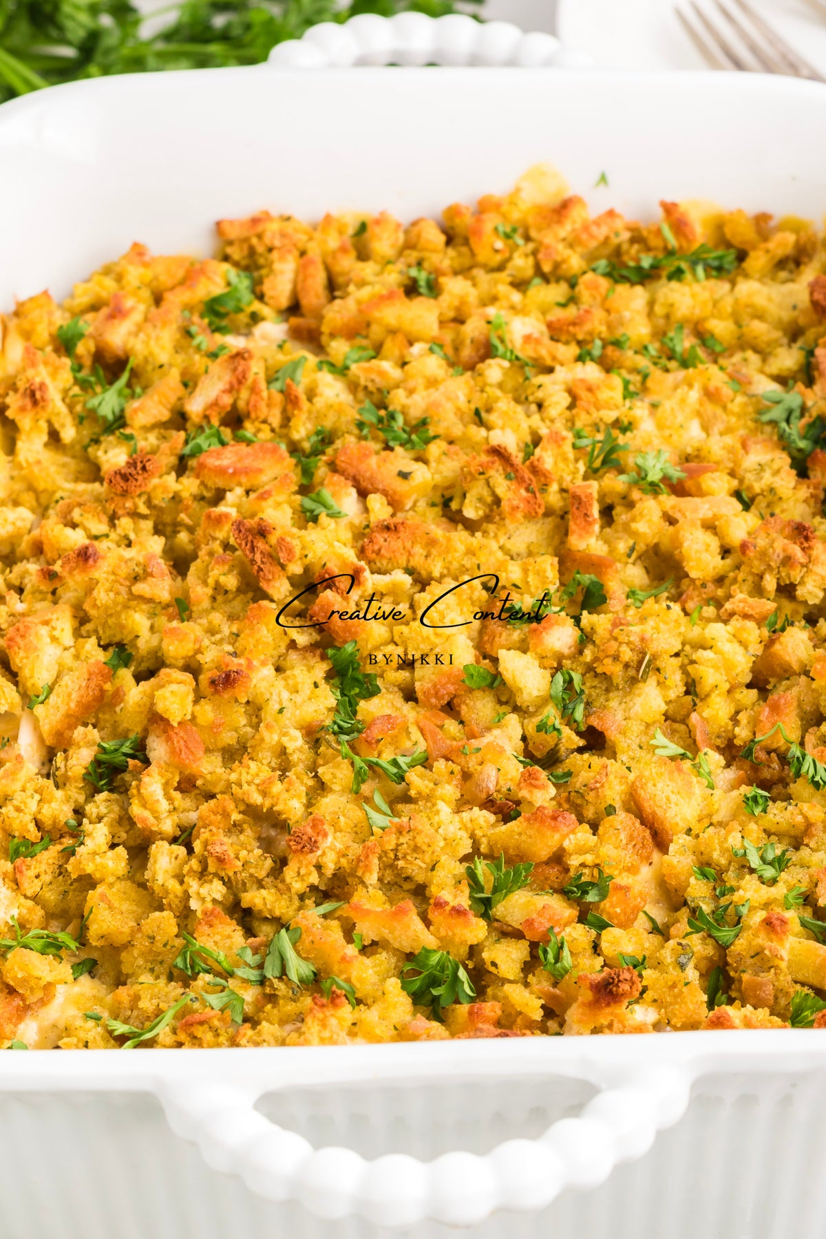 Church cookbook chicken casserole with a golden breadcrumb topping and fresh parsley in a white baking dish