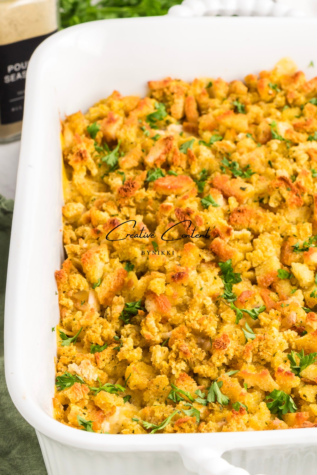 A white rectangular casserole dish filled with Church Cookbook Chicken Casserole - Exclusive, topped with fresh parsley.