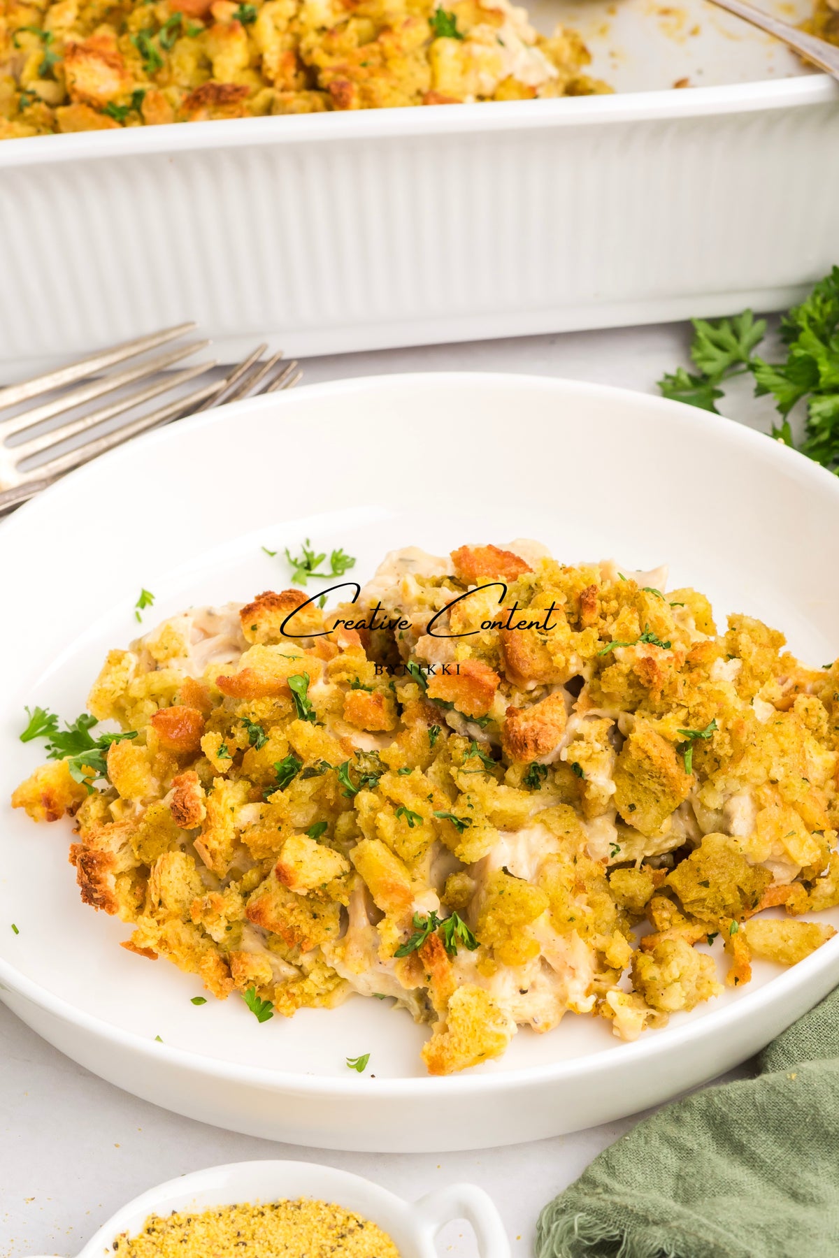 A serving of Church Cookbook Chicken Casserole - Exclusive in a white bowl, topped with golden brown stuffing.