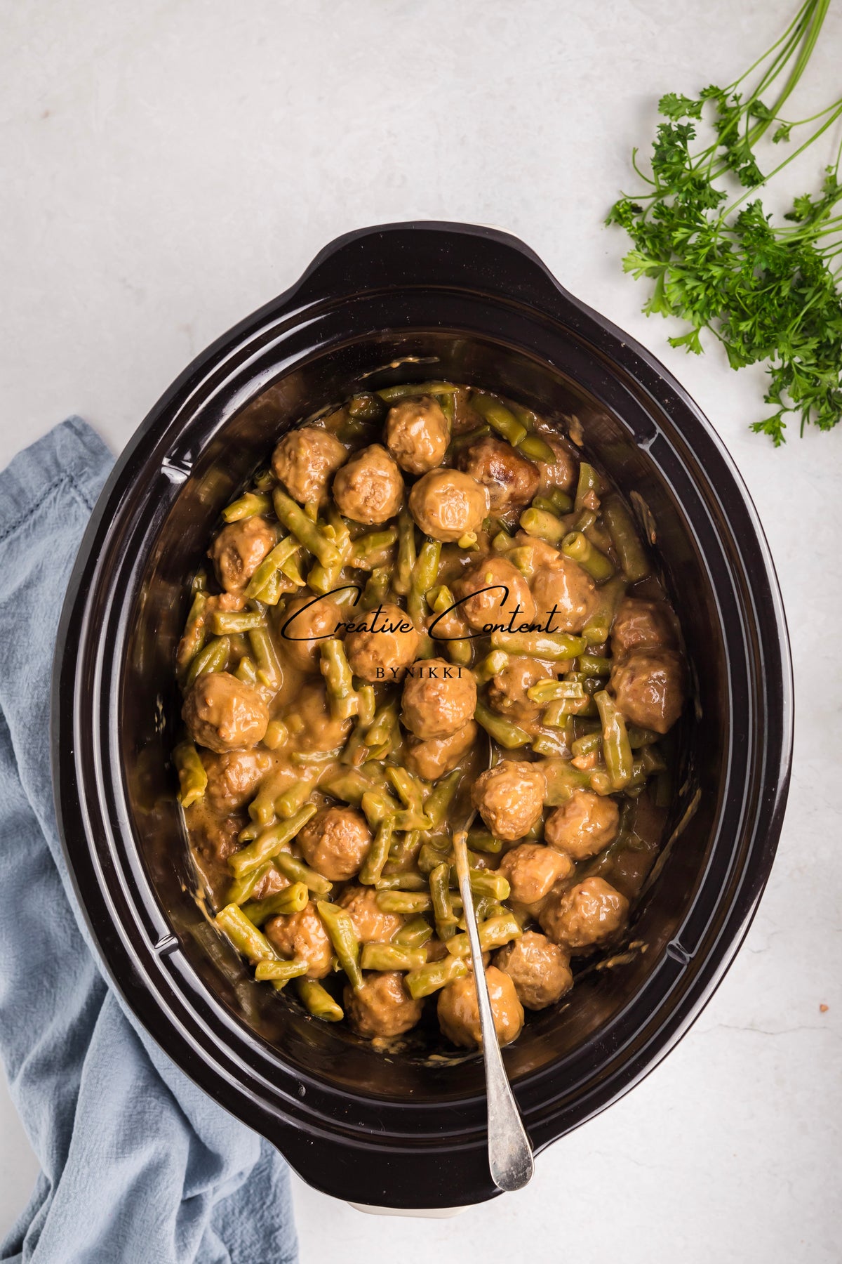 Slow cooker filled with Crock Pot Smothered Meatballs and Green Beans - Exclusive in a brown gravy.
