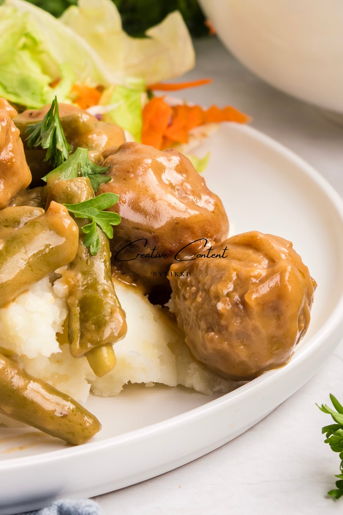 Crock Pot Smothered Meatballs and Green Beans in a savory brown gravy served over mashed potatoes.