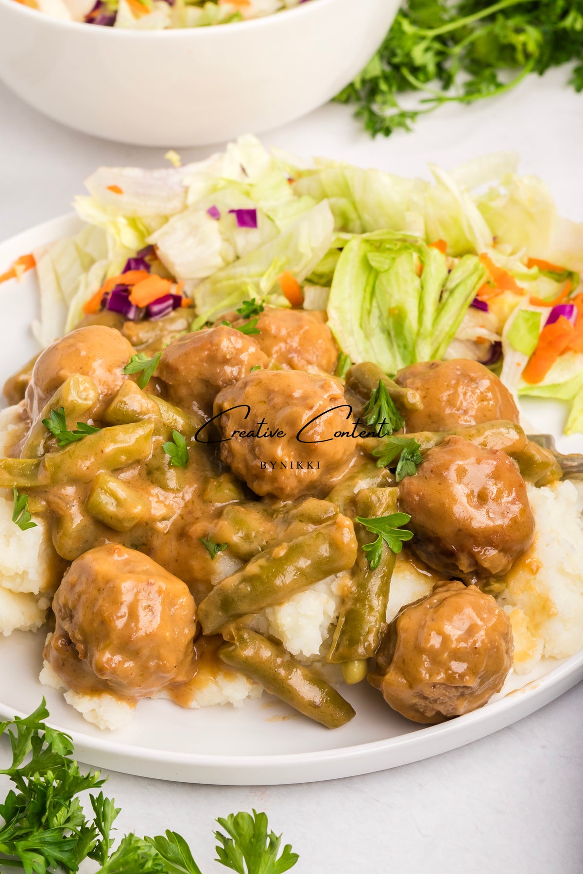 Crock Pot Smothered Meatballs and Green Beans - Exclusive served in a savory brown gravy over mashed potatoes with a side salad.