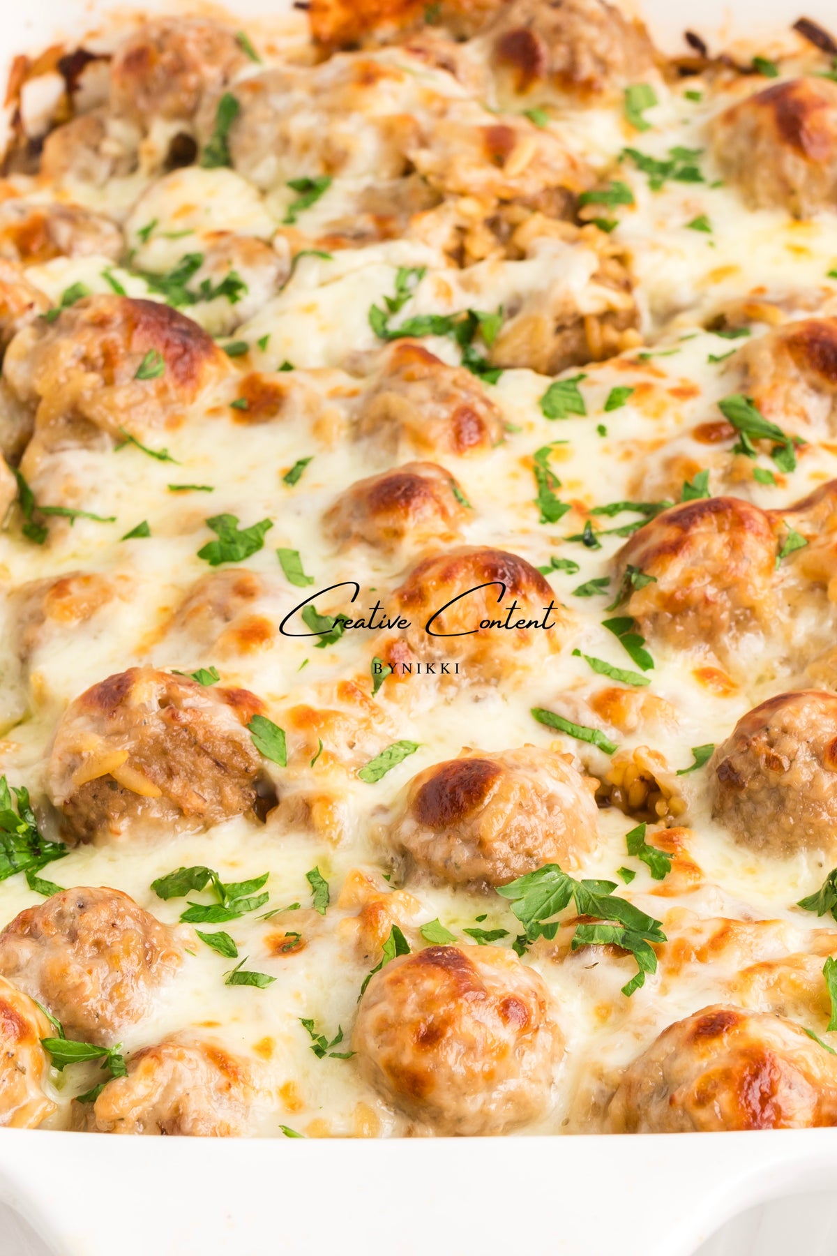 French Onion Meatball Orzo Bake topped with melted cheese and fresh parsley