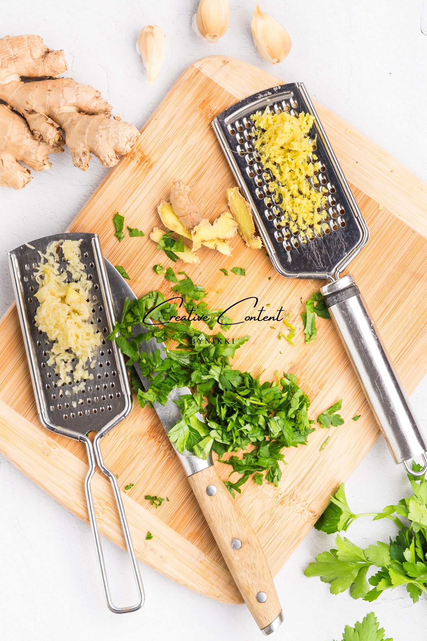 cutting board with knife, graters, garlic and ginger. 