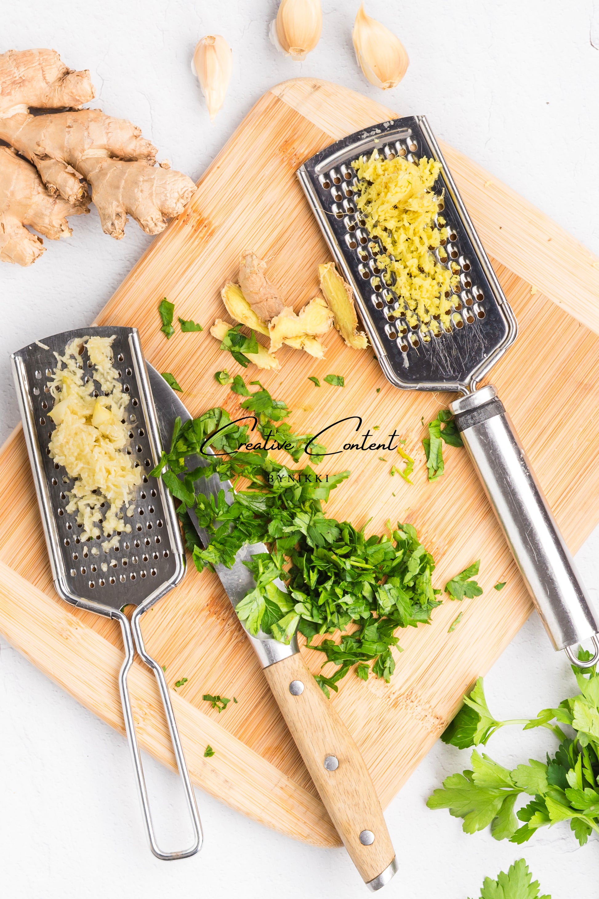 cutting board with knife, graters, garlic and ginger. 