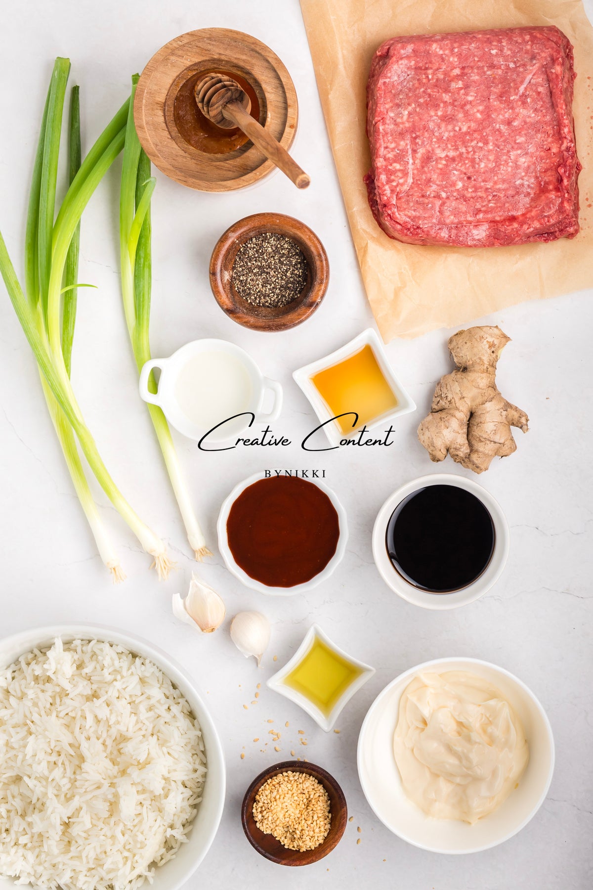 Top-down view of ingredients for Korean Beef Bulgogi - Exclusive, including ground meat, cooked rice, green onions, ginger, garlic, sesame seeds, and small bowls of gochujang sauce, honey, soy sauce, oil, and various condiments.
