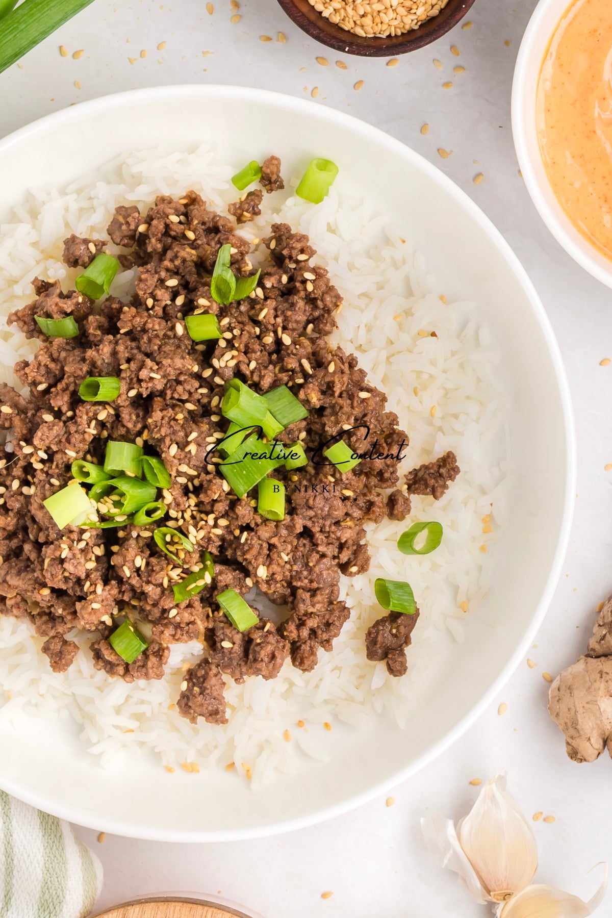 A bowl of Korean Beef Bulgogi - Exclusive topped with sesame seeds and green onions, served over white rice.