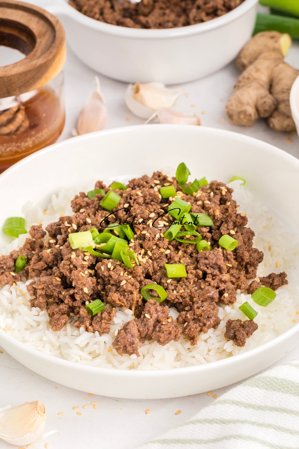 A bowl of Korean Beef Bulgogi - Exclusive, featuring ground beef in a savory gochujang sauce topped with sesame seeds and chopped green onions over white rice.