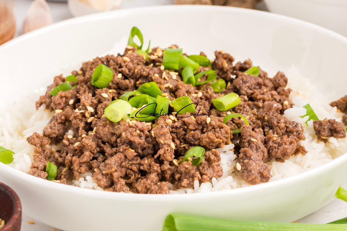 Korean Beef Bulgogi - Exclusive: ground beef with gochujang sauce, sesame seeds, and chopped green onions served over white rice in a white bowl.