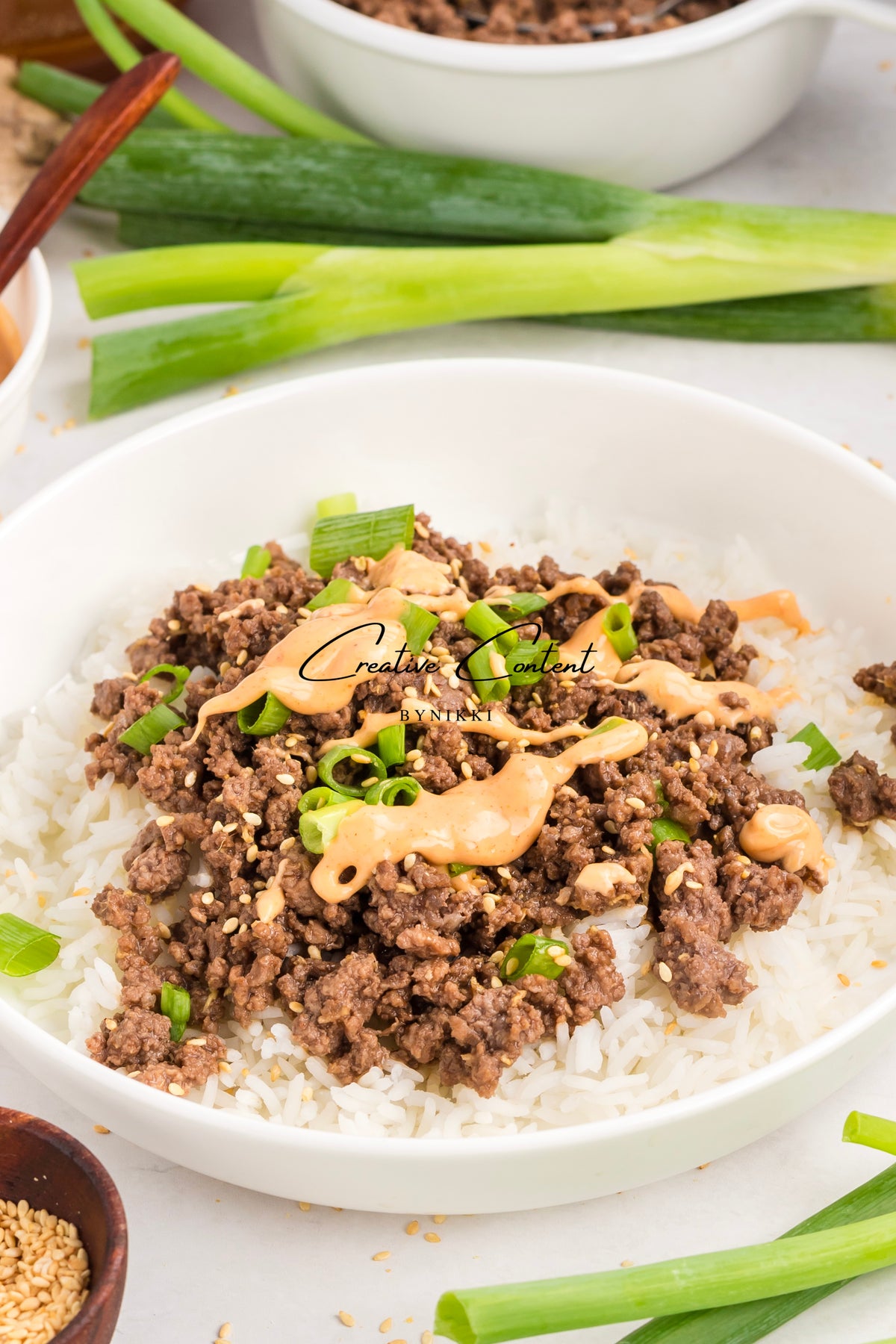 Korean Beef Bulgogi - Exclusive featuring ground beef in a spicy gochujang sauce served over white rice in a bowl, topped with sesame seeds and green onions.