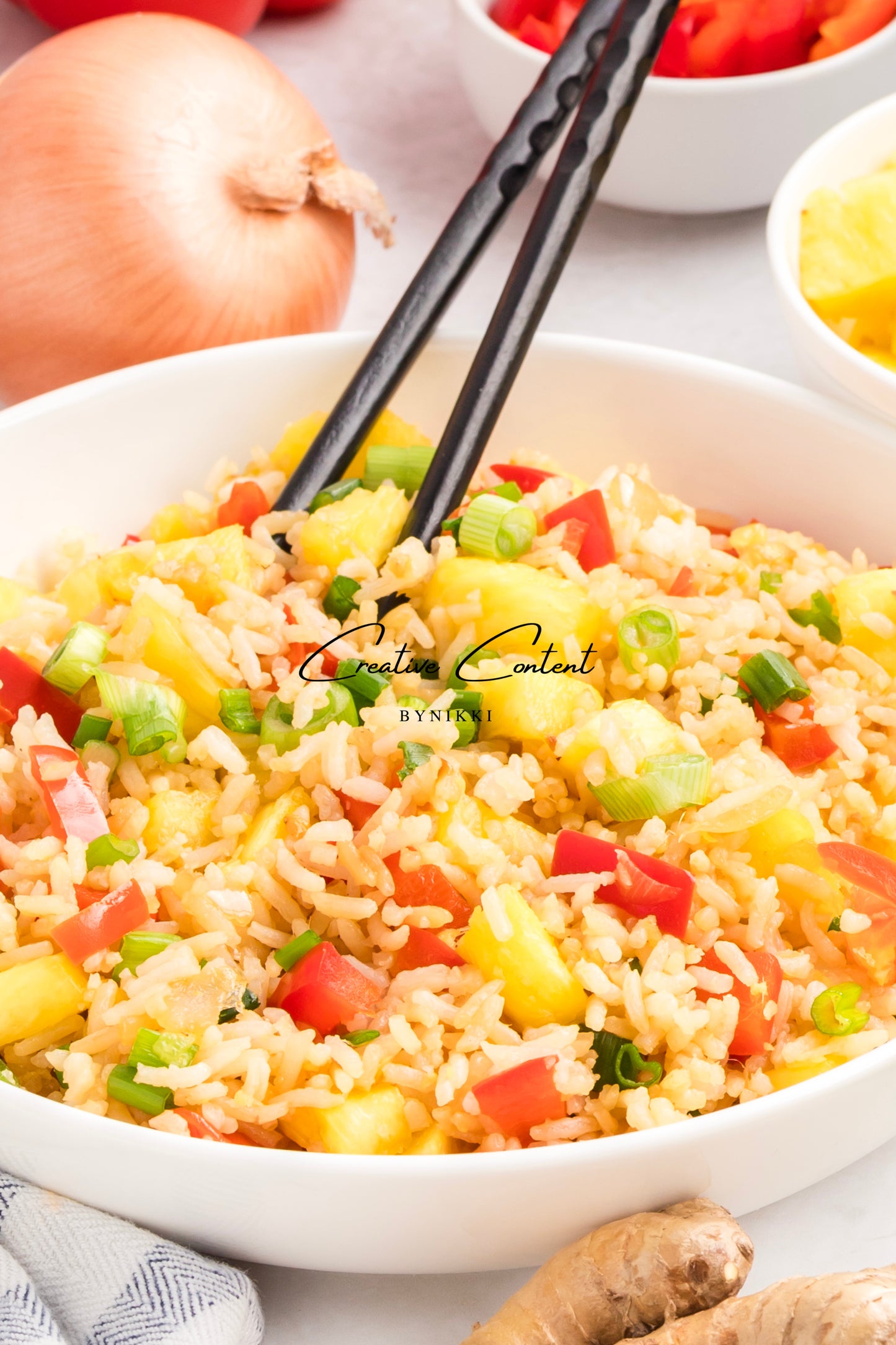 Bowl of fried rice with vegetables and chopsticks on a light background
