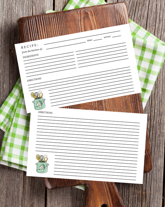 Two recipe cards on a wooden cutting board with green checkered cloth underneath.