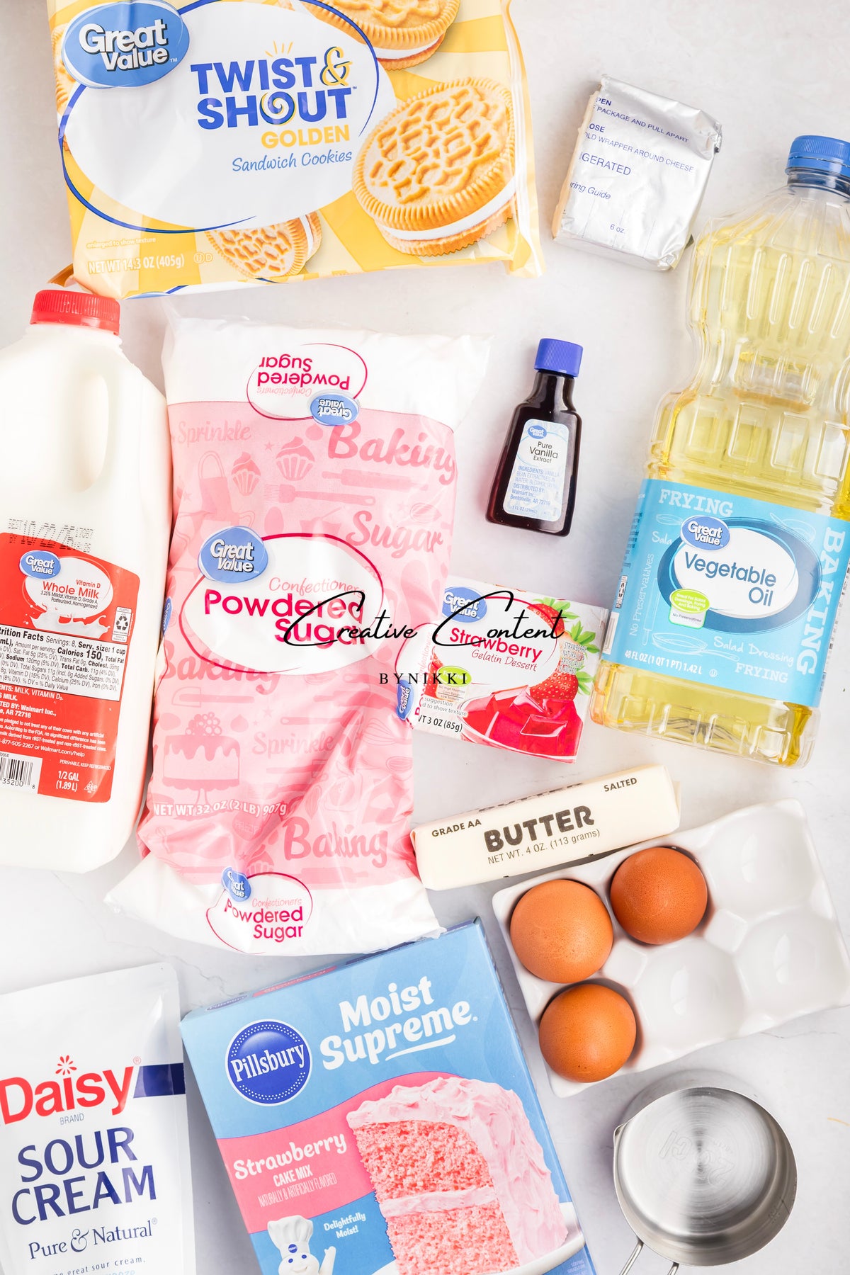 Ingredients for a Strawberry Crunch Cake - Exclusive, including strawberry cake mix, powdered sugar, gelatin, sandwich cookies, milk, oil, butter, sour cream, eggs, vanilla extract, and cream cheese for the vanilla frosting.