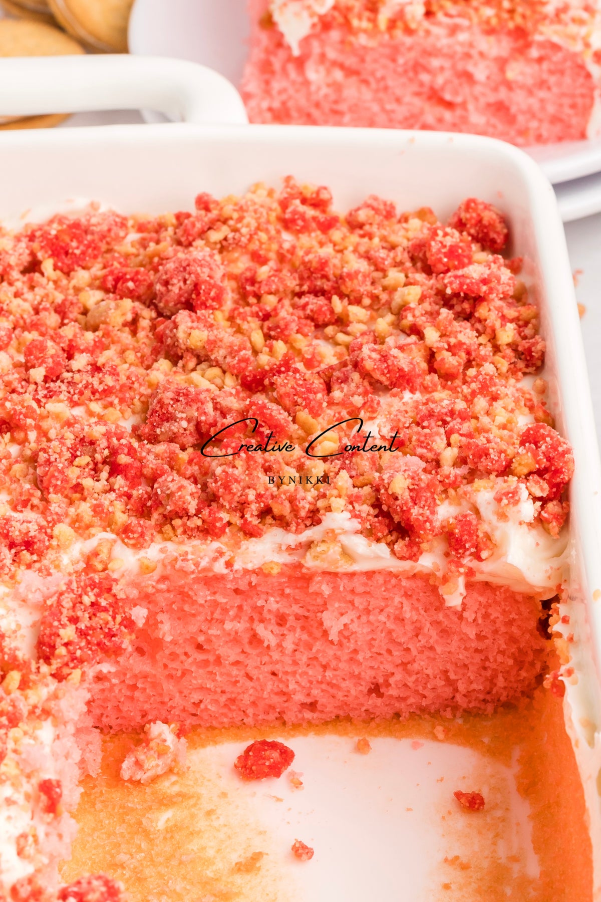 Strawberry Crunch Cake - Exclusive in a white baking dish, topped with a layer of red cookie crumble.