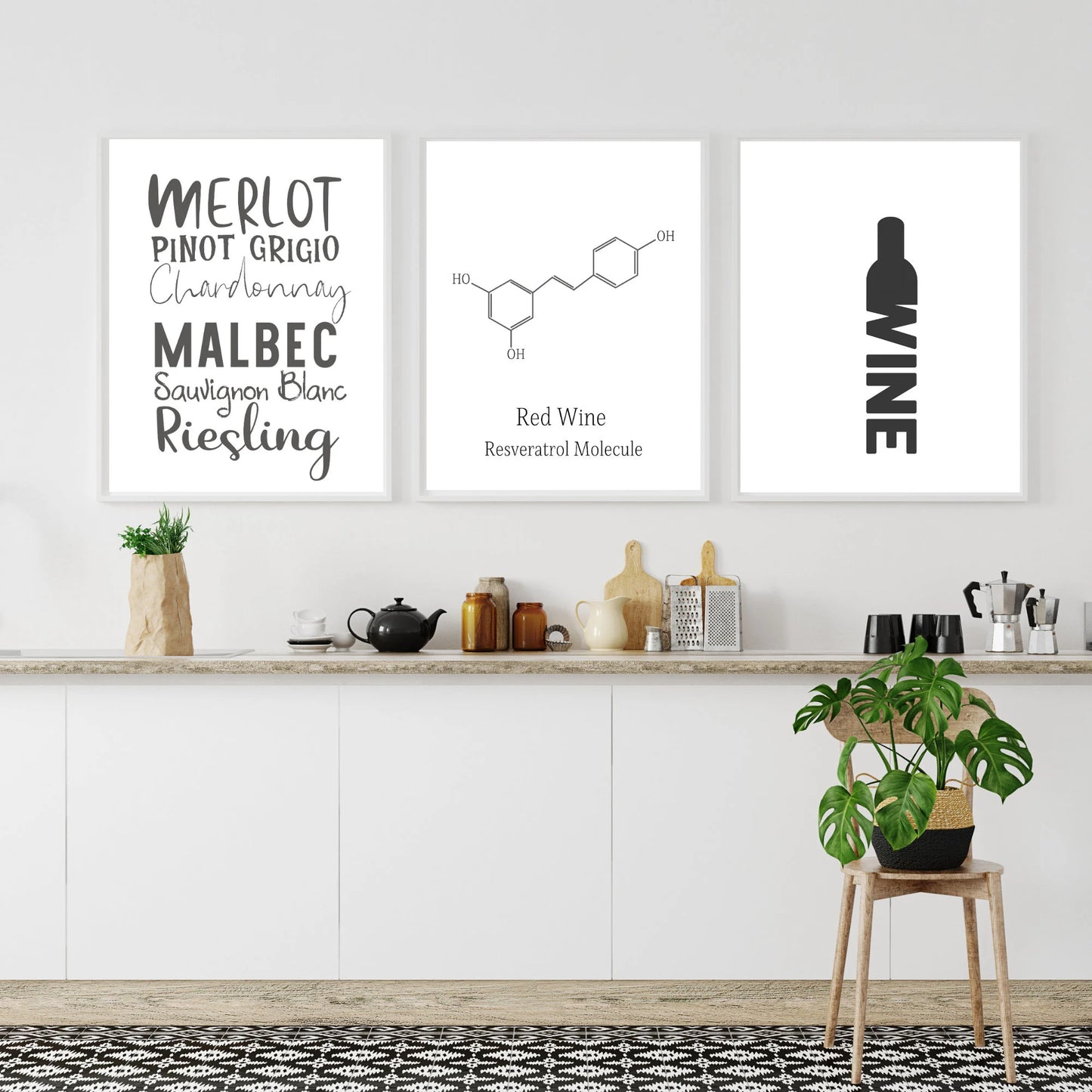 Three framed prints on a wall above a kitchen counter with wine-themed designs.