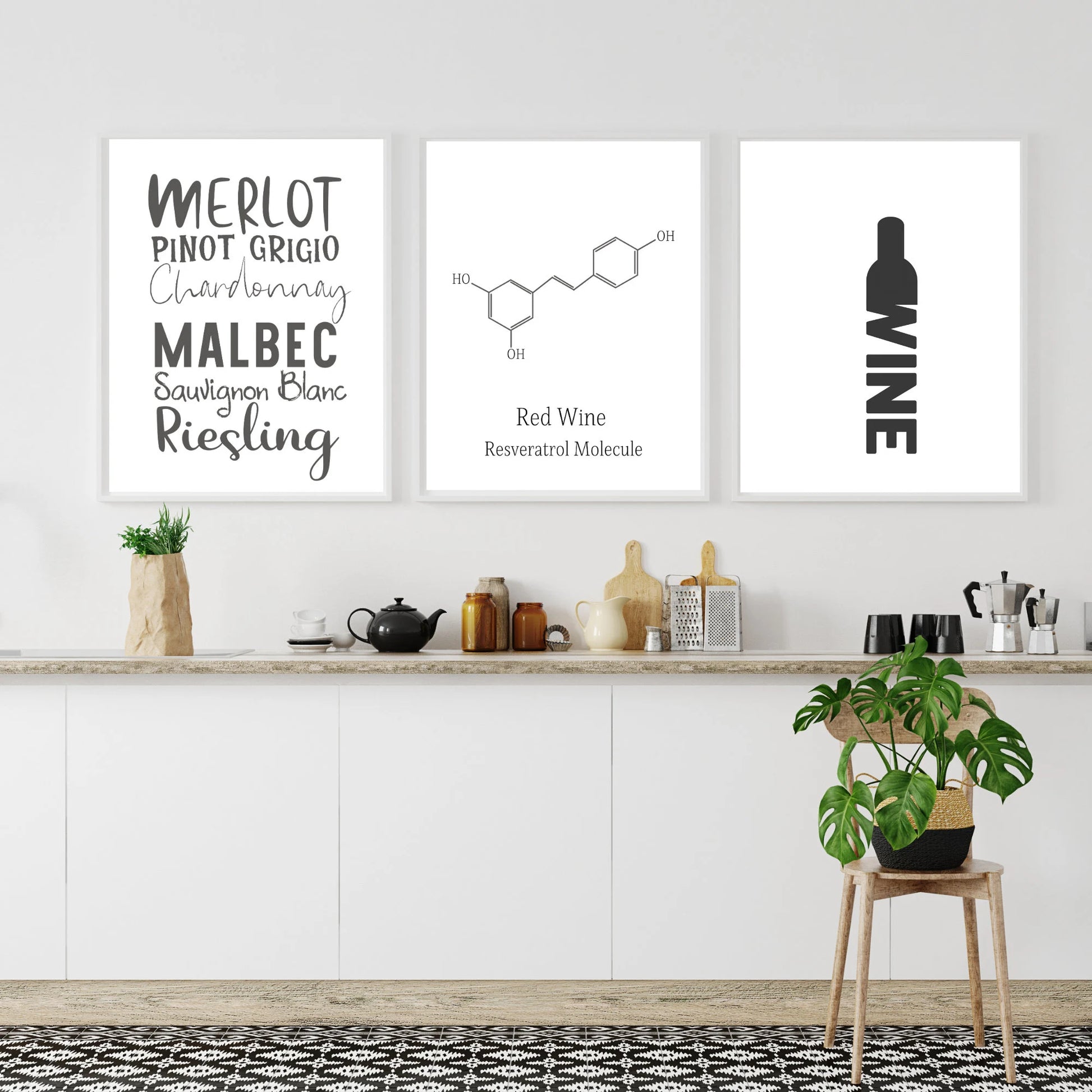 Three framed prints on a wall above a kitchen counter with wine-themed designs.